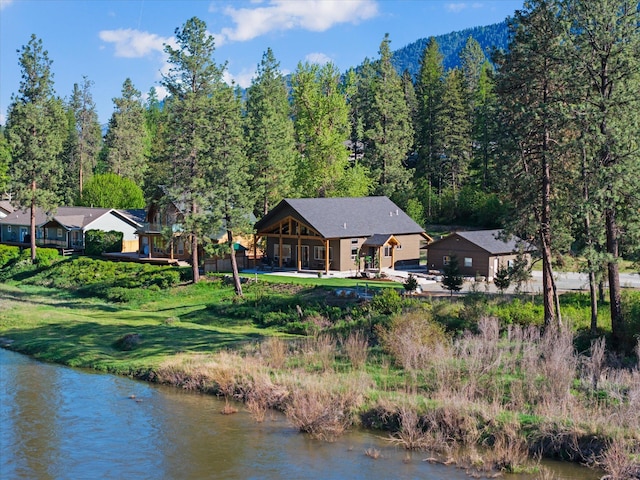 back of house with a view of trees and a water view