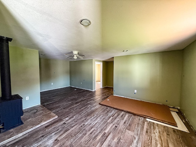 485 Wilson Butte Rd, Great Falls, MT 59405 - unfurnished living room featuring a wood stove, wood finished floors, ceiling fan, baseboards, and a textured ceiling