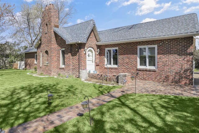3313 5th Ave N, Great Falls, MT 59401 - tudor-style house with a chimney, brick siding, a front lawn, a patio area, and roof with shingles