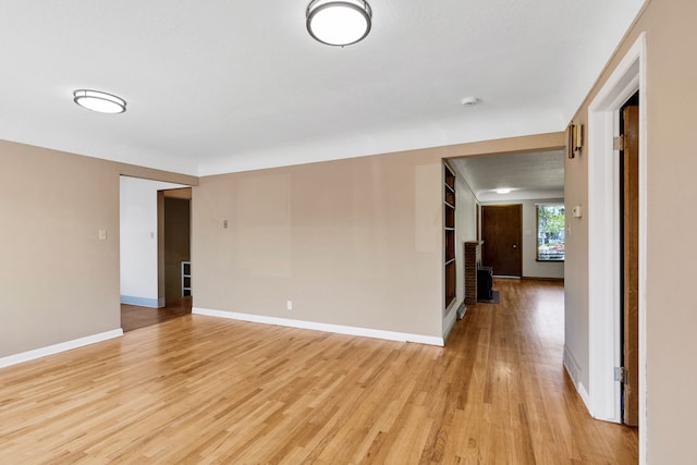 spare room featuring light wood-style floors, baseboards, and a smoke detector