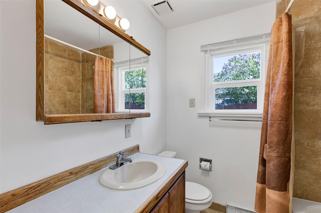 bathroom featuring toilet, tiled shower, and vanity
