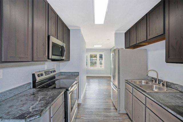 1221 7th Ave, Havre, MT 59501 - kitchen featuring appliances with stainless steel finishes, light wood-style flooring, dark brown cabinetry, and dark countertops