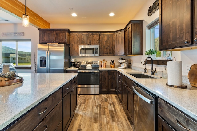 21087 Pamin Loop, Clinton, MT 59825 - kitchen with appliances with stainless steel finishes, light wood-type flooring, light stone counters, dark brown cabinets, and hanging light fixtures