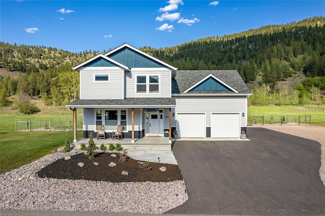 21087 Pamin Loop, Clinton, MT 59825 - view of front of home with a forest view, a porch, a garage, driveway, and roof with shingles