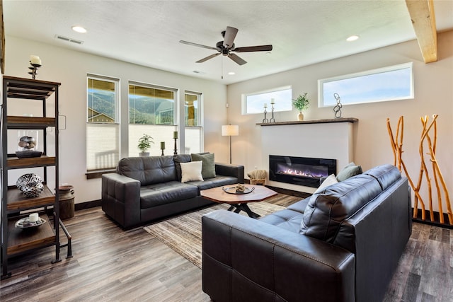 living room with a glass covered fireplace, a ceiling fan, wood finished floors, recessed lighting, and baseboards