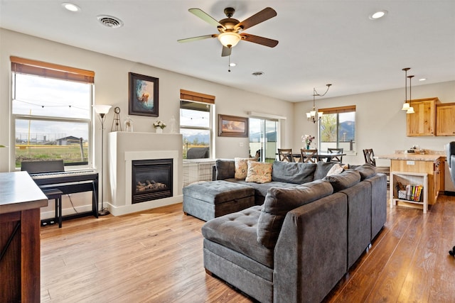 1317 Creekside Dr, Stevensville, MT 59870 - living room featuring a ceiling fan, recessed lighting, light wood-type flooring, a glass covered fireplace, and a chandelier