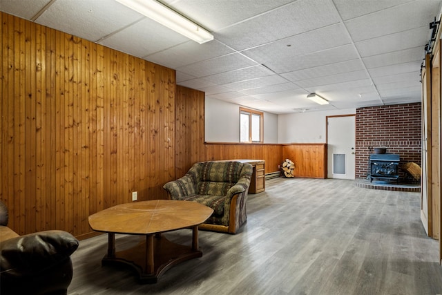 445 Sapphire Ln, Stevensville, MT 59870 - living area with wood walls, a wood stove, wood finished floors, and a paneled ceiling