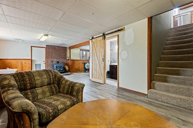 445 Sapphire Ln, Stevensville, MT 59870 - living room with a wood stove, wood finished floors, stairs, wooden walls, and a paneled ceiling
