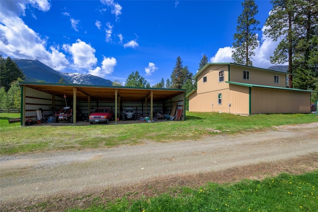 1500 River Rd W, Plains, MT 59859 - view of vehicle parking featuring dirt driveway, a mountain view, a detached carport, and an outbuilding