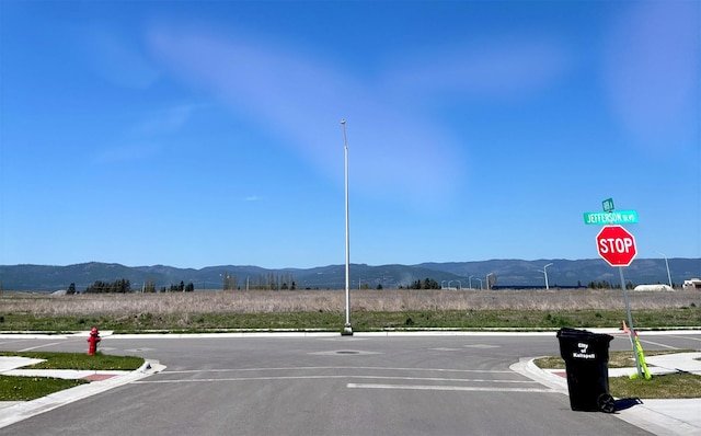 2195 Black Bird Ln, Kalispell, MT 59901 - view of asphalt street featuring curbs, a mountain view, sidewalks, and traffic signs