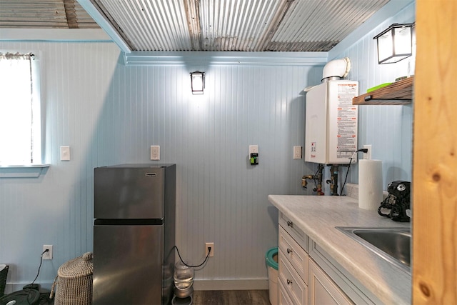 4358 Charlotte Way, Stevensville, MT 59870 - kitchen featuring freestanding refrigerator, tankless water heater, dark wood-type flooring, white cabinetry, and light countertops