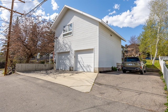 view of side of home featuring concrete driveway, an attached garage, and fence