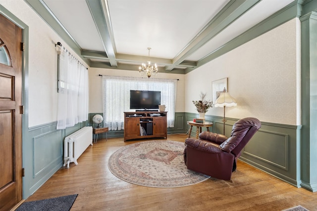 living room featuring radiator heating unit, a chandelier, wainscoting, coffered ceiling, and beam ceiling
