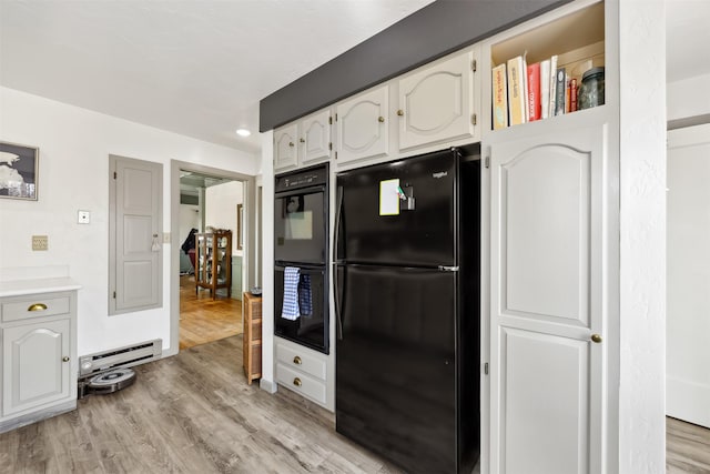 kitchen with black appliances, light wood finished floors, a baseboard radiator, white cabinetry, and light countertops