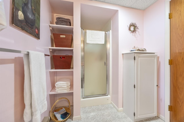 bathroom with a shower stall and baseboards