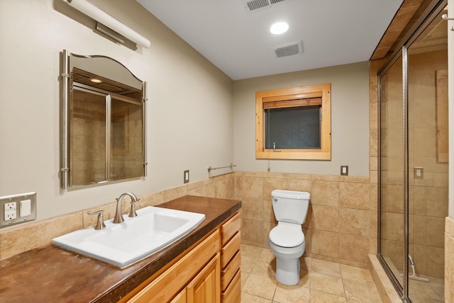 full bathroom featuring tile patterned floors, a shower stall, tile walls, toilet, and vanity