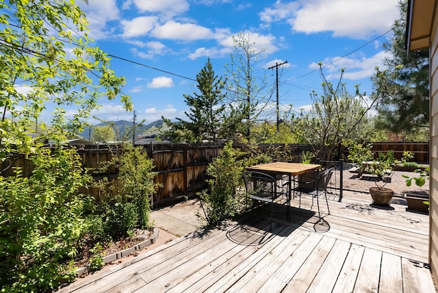 wooden deck with outdoor dining area and a fenced backyard