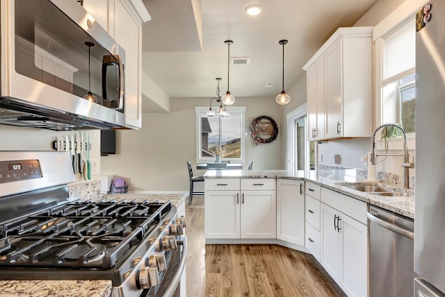 7047 Shaver Dr Unit B, Missoula, MT 59803 - kitchen with appliances with stainless steel finishes, light wood-style floors, a sink, a peninsula, and white cabinetry