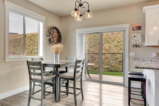 7047 Shaver Dr Unit B, Missoula, MT 59803 - dining area with healthy amount of natural light, light wood-type flooring, baseboards, and a chandelier