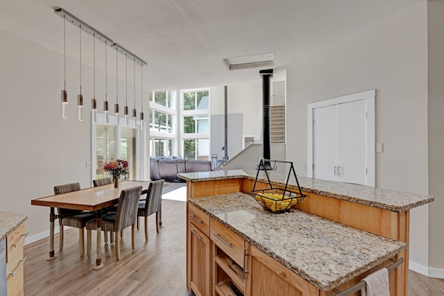 11327 Sleeman Ln, Lolo, MT 59847 - kitchen featuring light wood-style flooring, a wood stove, baseboards, light stone countertops, and a center island