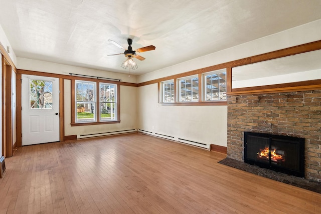 427 Somers Ave, Whitefish, MT 59937 - unfurnished living room featuring a ceiling fan, wood-type flooring, a baseboard radiator, and a brick fireplace