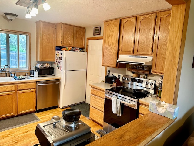 146 New Meadows Dr, Missoula, MT 59808 - kitchen featuring stainless steel appliances, under cabinet range hood, light countertops, light wood finished floors, and a textured ceiling