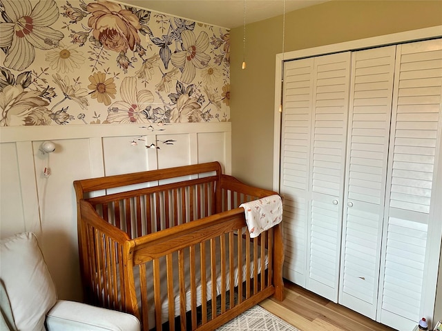 146 New Meadows Dr, Missoula, MT 59808 - bedroom featuring wallpapered walls, a wainscoted wall, a decorative wall, light wood-style floors, and a crib