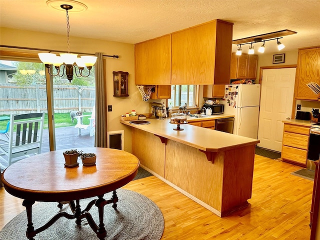 146 New Meadows Dr, Missoula, MT 59808 - kitchen with freestanding refrigerator, dishwashing machine, light countertops, a chandelier, and a peninsula