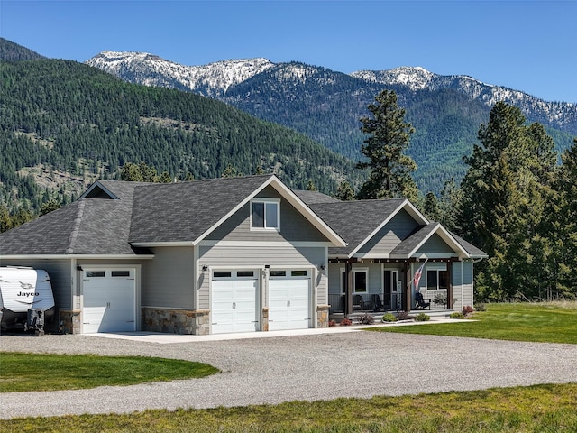 29 Elk Run Trl, Kalispell, MT 59901 - view of front facade with a garage, a porch, a mountain view, and stone siding