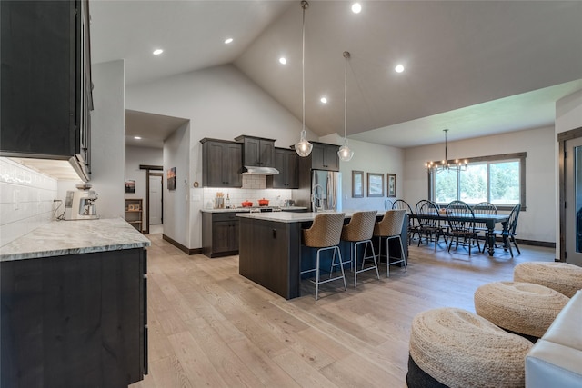 29 Elk Run Trl, Kalispell, MT 59901 - kitchen featuring stainless steel fridge, a breakfast bar area, light countertops, a center island with sink, and high vaulted ceiling