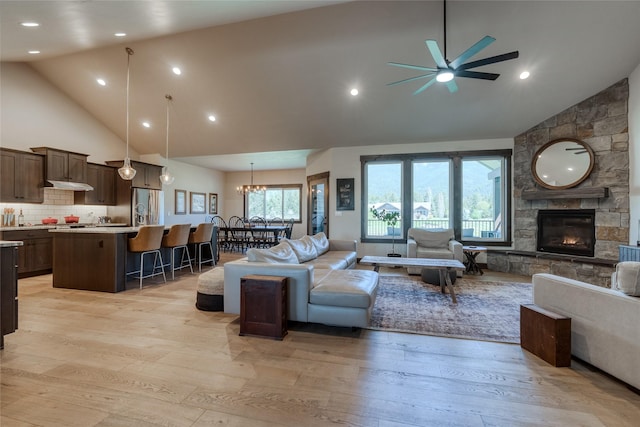 29 Elk Run Trl, Kalispell, MT 59901 - living room with high vaulted ceiling, a ceiling fan, light wood-style flooring, a stone fireplace, and a chandelier