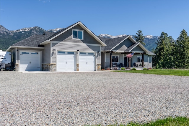 29 Elk Run Trl, Kalispell, MT 59901 - craftsman-style home featuring a porch, a mountain view, an attached garage, stone siding, and driveway