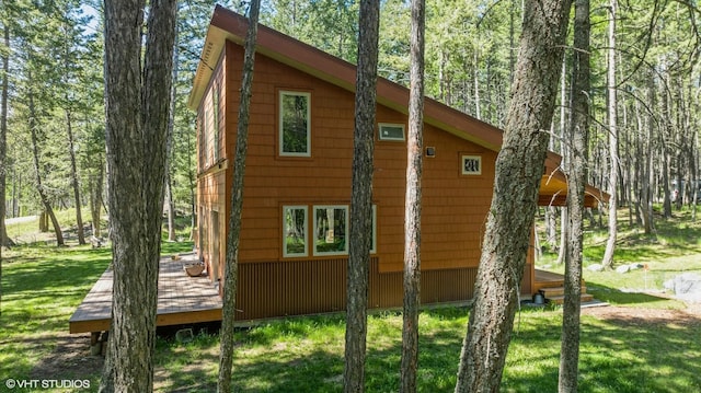 view of side of home with a wooden deck and a yard