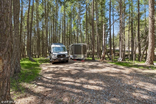 view of vehicle parking with a view of trees