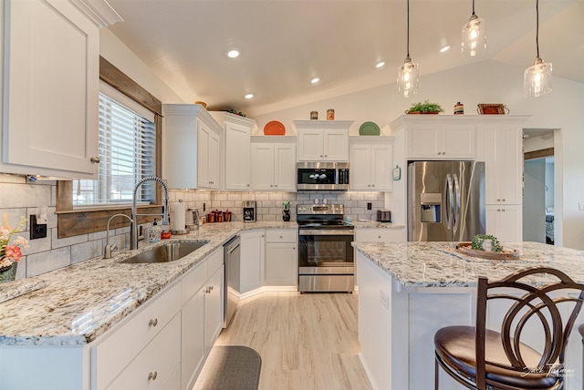 2966 Vermillion Way E, Helena, MT 59635 - kitchen featuring appliances with stainless steel finishes, lofted ceiling, white cabinetry, decorative backsplash, and a kitchen bar