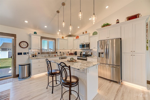 2966 Vermillion Way E, Helena, MT 59635 - kitchen featuring appliances with stainless steel finishes, vaulted ceiling, light wood finished floors, tasteful backsplash, and recessed lighting