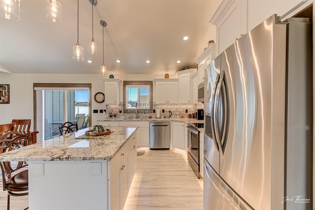 2966 Vermillion Way E, Helena, MT 59635 - kitchen featuring appliances with stainless steel finishes, white cabinets, a kitchen breakfast bar, recessed lighting, and decorative backsplash