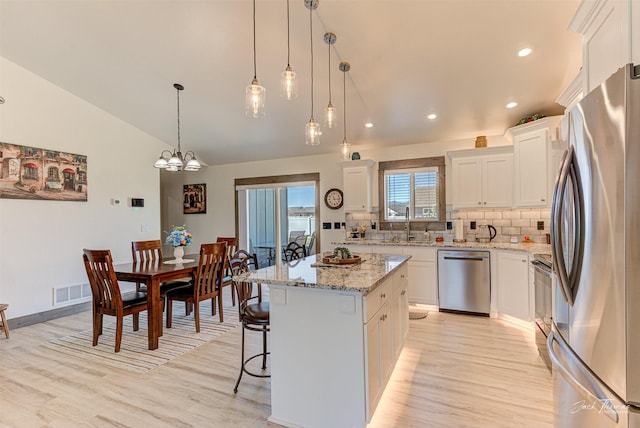 2966 Vermillion Way E, Helena, MT 59635 - kitchen with stainless steel appliances, light wood finished floors, tasteful backsplash, a kitchen island, and lofted ceiling