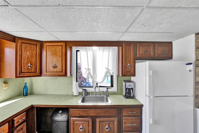 1320 1st Ave S, Great Falls, MT 59401 - kitchen featuring freestanding refrigerator, a sink, light countertops, brown cabinetry, and a drop ceiling