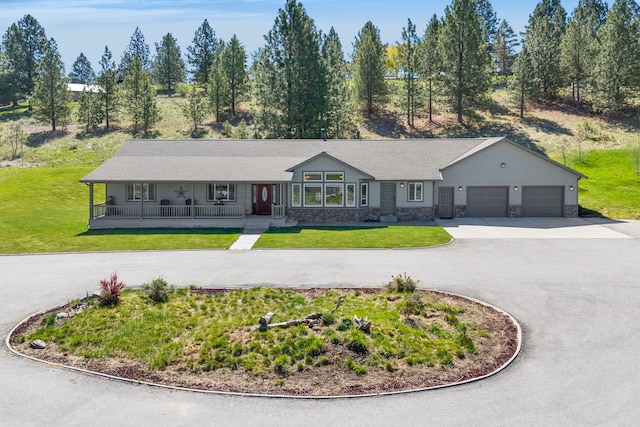 single story home featuring curved driveway, a porch, a garage, and a front lawn