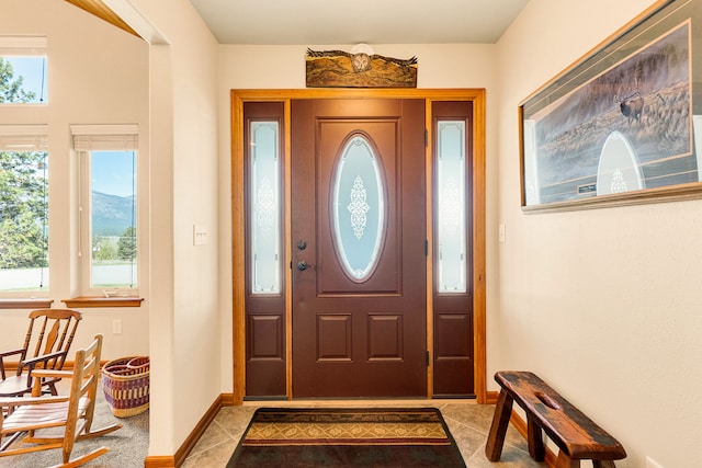 foyer with healthy amount of natural light, light tile patterned flooring, and baseboards