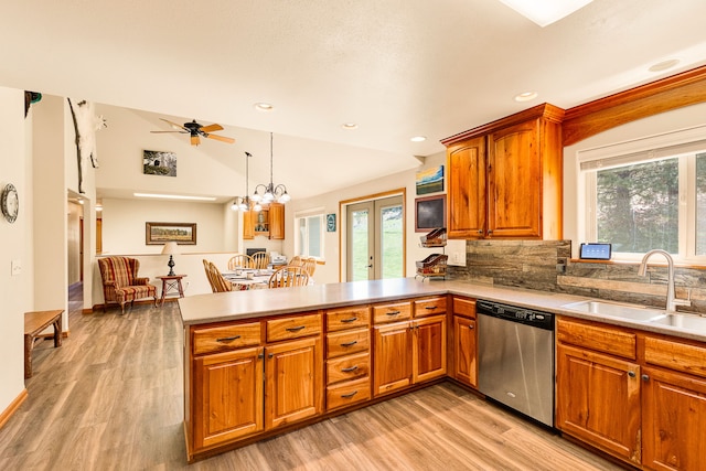 kitchen featuring stainless steel dishwasher, a sink, a peninsula, healthy amount of natural light, and lofted ceiling
