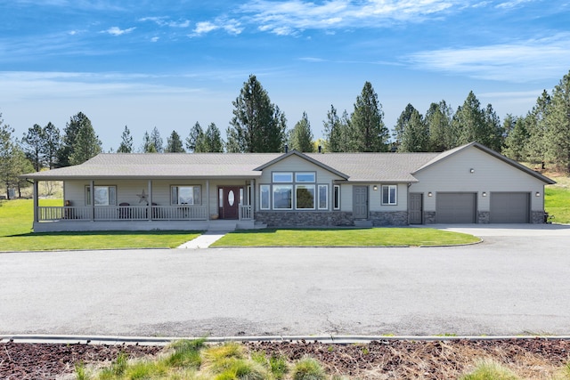 ranch-style house with covered porch, a garage, a front yard, concrete driveway, and stone siding