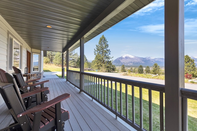 wooden deck with a mountain view and a lawn