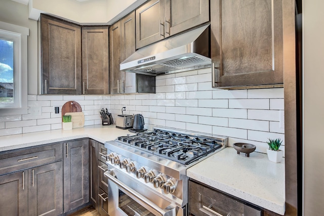 217 Spring St, Townsend, MT 59644 - kitchen featuring high end stainless steel range, under cabinet range hood, backsplash, and dark brown cabinets