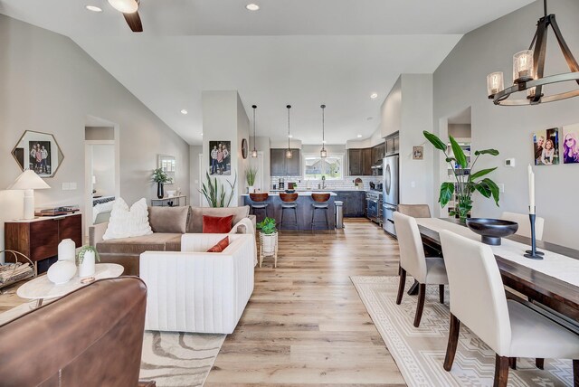 living area with vaulted ceiling, light wood-style floors, ceiling fan, and recessed lighting