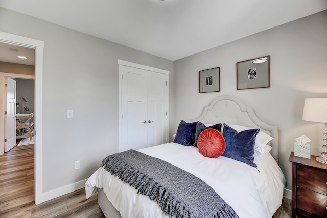 bedroom with baseboards, wood finished floors, and a closet