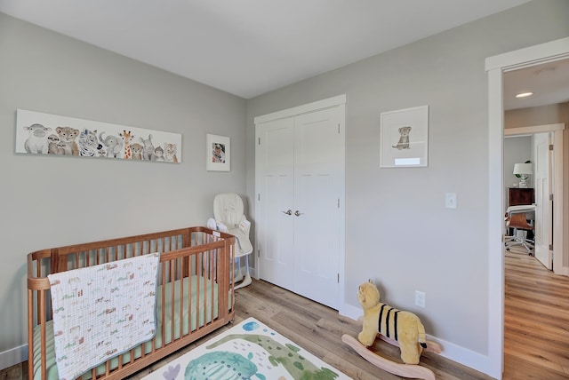 bedroom featuring wood finished floors, baseboards, and a closet