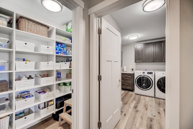 laundry room featuring washer and dryer, cabinet space, and light wood-type flooring