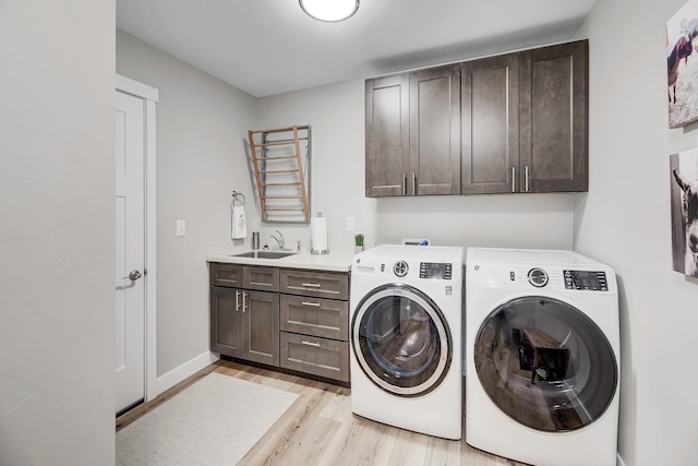 clothes washing area with cabinet space, washer and dryer, and light wood-style flooring
